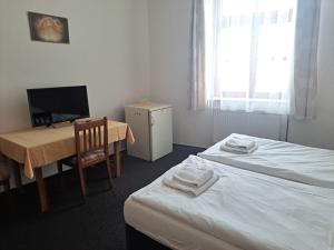 a room with two beds and a table and a television at Hotel Praděd in Jeseník