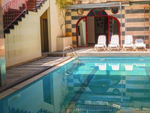 a swimming pool with lounge chairs and a house at Lebanon Hostel in Makhāḑat Nahr al Kalb