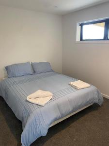 a bed in a white room with two towels on it at Pukutahi Palms in Te Anau