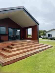 a house with a large wooden deck on the grass at Pukutahi Palms in Te Anau