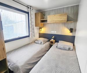two beds in a room with a window at Séjour en Forêt 4 étoiles in Litteau +18 photos
