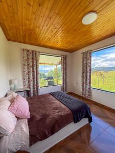 a bedroom with a large bed and a large window at Finca Siberia, Sisga in Tilatá