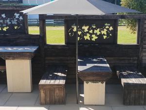 a picnic shelter with benches and an umbrella at Marshall's Haven in Hahei +1 photo