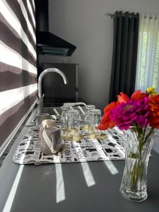 a table with a vase of flowers and glasses on it at Lexhulo Room's in Domje