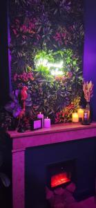 a fireplace with candles and a wall with plants at Suite Passion - Jacuzzi privé - Table massage in Saint-Étienne