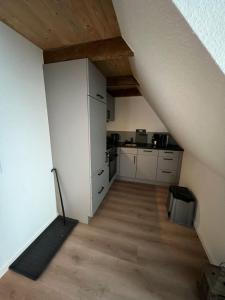 an attic room with a kitchen and a staircase at Auental in Husum +3 photos