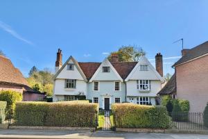 a white house with a fence and bushes at Manor Cottage in Cavendish