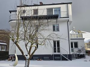 a white building with a tree in front of it at Apartamenty Aquarius - Latarnik in Gdynia