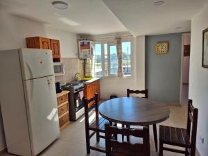 a kitchen with a table and a white refrigerator at Rent Santa Clara in Santa Clara del Mar