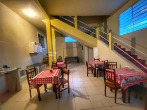 a dining room with tables and chairs and a staircase at Casarão Hostel in Guaratinguetá