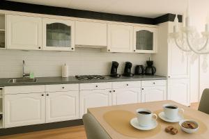 a kitchen with white cabinets and a table with two cups at Moonlight Nature Holiday Home in Westergeest