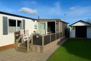 a deck with two chairs and a table on a house at Moonlight Nature Holiday Home in Westergeest +4 photos