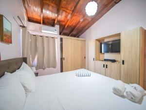 a bedroom with a large white bed and a tv at Colonial 2BR Apartment 2 mins walk to beach in Sosúa