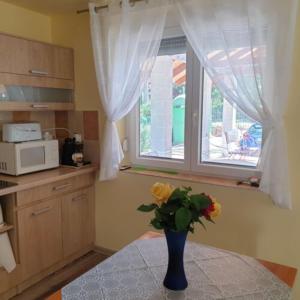 a vase with flowers sitting on a table in a kitchen at Villa Bella in Szántód