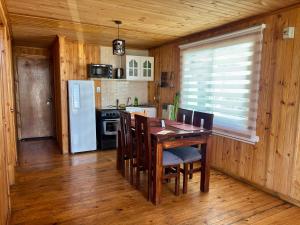 a kitchen with a table and chairs and a refrigerator at Cabañas EcoSur - Chile in Curacautín