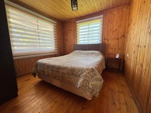 a bedroom with a bed in a wooden room at Cabañas EcoSur - Chile in Curacautín