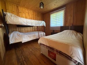 two bunk beds in a room with wooden walls at Cabañas EcoSur - Chile in Curacautín +13 photos