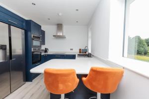 a kitchen with a white counter and orange chairs at Buzzards Retreat in Tiverton