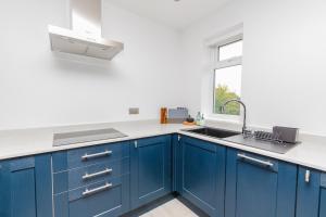 a blue kitchen with a sink and a window at Buzzards Retreat in Tiverton