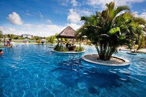 a resort swimming pool with a palm tree and a gazebo at Iloa Studio Alagoas conforto e encantamento in Barra de São Miguel