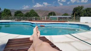 a person sitting on a bench next to a swimming pool at Sayacuna Huasi Cabañas in Tafí del Valle