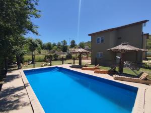 a large swimming pool with chairs and umbrellas at La Serena Cabañas in Potrero de los Funes