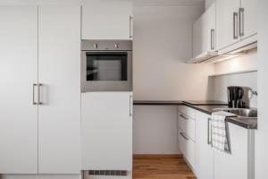 a white kitchen with white cabinets and a sink at Central-Trondheim Riverside Studio-Apartment in Trondheim
