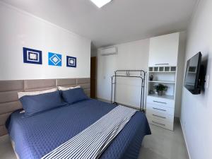 a bedroom with a blue bed and a tv at Apartamento 1001 in Guarapari