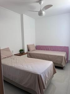 two beds in a room with a ceiling fan at Apartamento 1001 in Guarapari