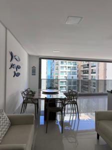 a living room with a table and chairs and a large window at Apartamento 1001 in Guarapari