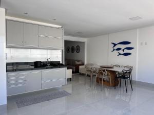 a kitchen with white cabinets and a table with chairs at Apartamento 1001 in Guarapari