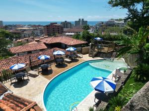 a view of a pool with umbrellas and chairs at Hotel Coquille in Ubatuba