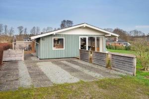 a green house with a patio in a yard at SJ316-Hejls-Ronnebaervaenget-9 in Hejlsminde