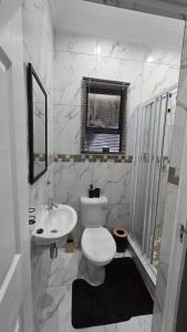 a white bathroom with a toilet and a sink at HUZULA Royal Residence in Empangeni +51 photos