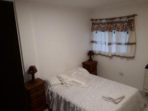 a bedroom with a bed with white sheets and a window at Tafi Apart in Sarmiento