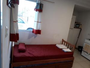 a small bedroom with a red bed and a window at Tafi Apart in Sarmiento +1 photo
