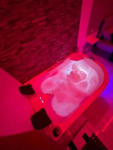 a bath tub with pink lights in a room at Suite GOLD Jacuzzi & Sauna privé I Centre Béziers Arrivée autonome 24h24 in Béziers
