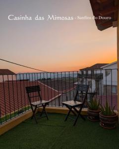 two chairs sitting on a balcony with the sunset at Casinha das Mimosas in Sanfins do Douro