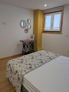 a bedroom with a bed with a table and a window at Casinha das Mimosas in Sanfins do Douro