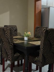 a black table and two chairs with a plant on it at Edmut Apartments in Lusaka +18 photos