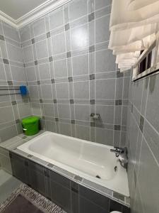 a bath tub in a bathroom with gray tiles at Edmut Apartments in Lusaka