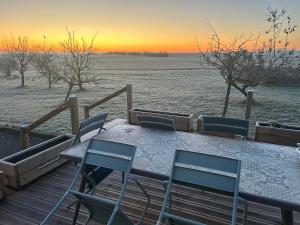 a table and chairs on a wooden deck with the sunset at Gîte de la Vigne in Ley