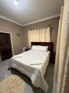 a bedroom with a large bed with white sheets and pillows at Edmut Apartments in Lusaka