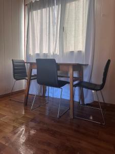 a dining room table with two chairs and a white curtain at Tu Espacio en Rada in Rada Tilly