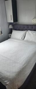 a large bed with white sheets and a blue headboard at Trecco Bay Private rentals in Newton