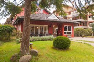 a red building with a tree in front of it at Pousada Tango in Gramado