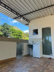 an outdoor patio with a white refrigerator and a window at Refúgio Rio Soberbo in Guapimirim