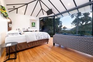a bedroom with a bed and a large window at Dantica Cloud Forest Lodge in San Gerardo de Dota