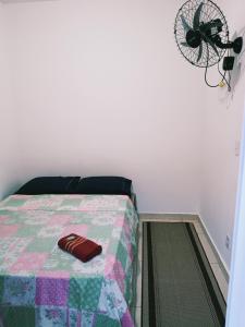 a bedroom with a bed with a quilt and a fan at Suites Aeroporto in Campinas