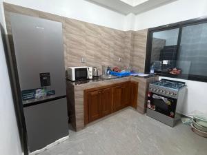 a small kitchen with a stove and a microwave at Résidence L H in Yaoundé